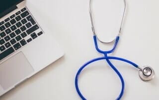 Stethoscope next to a laptop